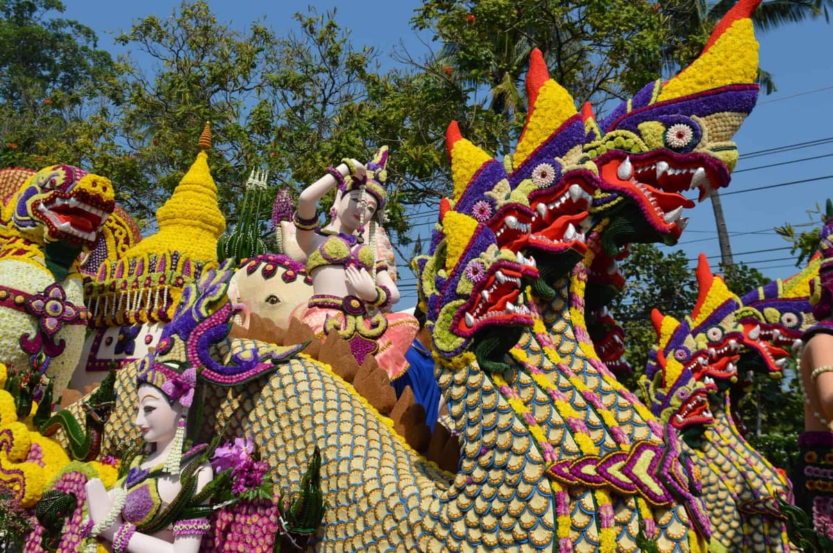 Parade float covered in flowers forming mythical naga dragons and figures at the Chiang Mai Flower Festival