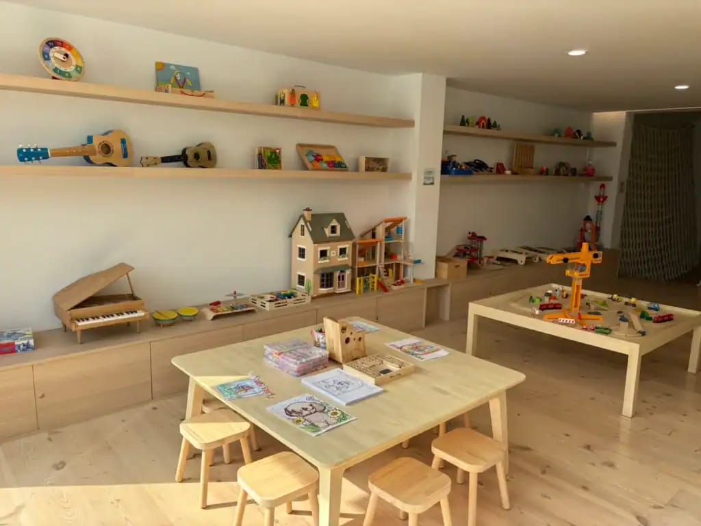 Wooden Ville Kids Cafe toy room with wooden Montessori toys, a dollhouse, toy piano and ukuleles on shelves