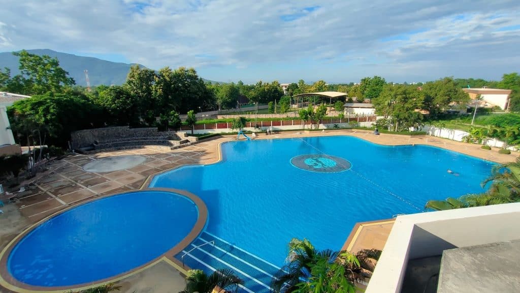 Sprawling free-form and round pools with a logo mosaic and mountain backdrop at World Club Land