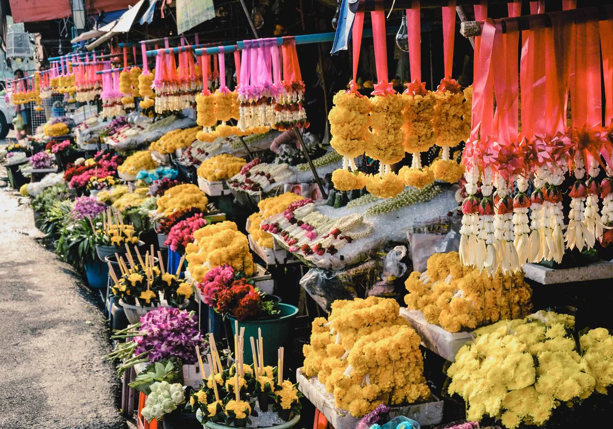 Thai market stall hung with rows of marigold garlands and flower offerings