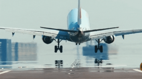 Passenger jet touching down on a wet runway, seen from behind