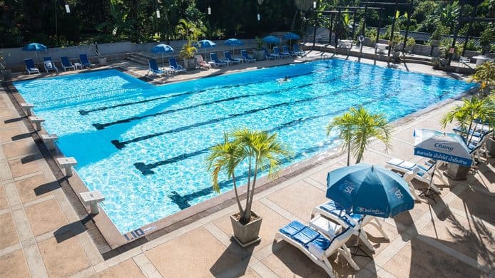 Eco Resort lap pool with dark lane lines, Chang-branded umbrellas and loungers among potted palms
