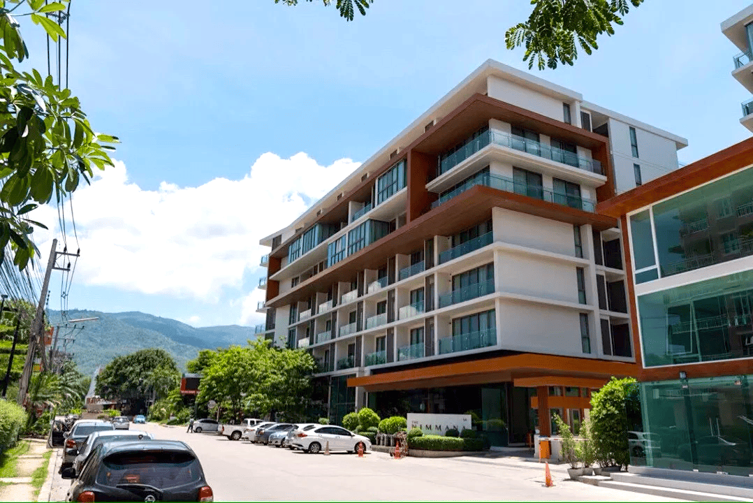 The Nimmana condominium, a modern high-rise on a quiet Nimmanhaemin street with mountains in the background