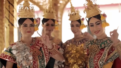 Four smiling Thai dancers in gilded headdresses and traditional costume