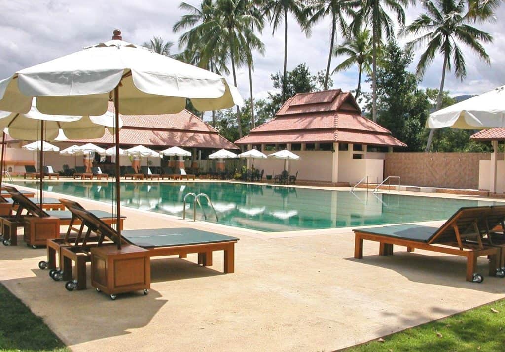 Center of the Universe saltwater pool ringed by coconut palms, white umbrellas and tiled-roof salas