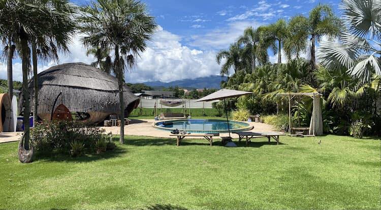 The Cocoon's round garden pool beside a shell-shaped thatched hut with mountain views in Hang Dong