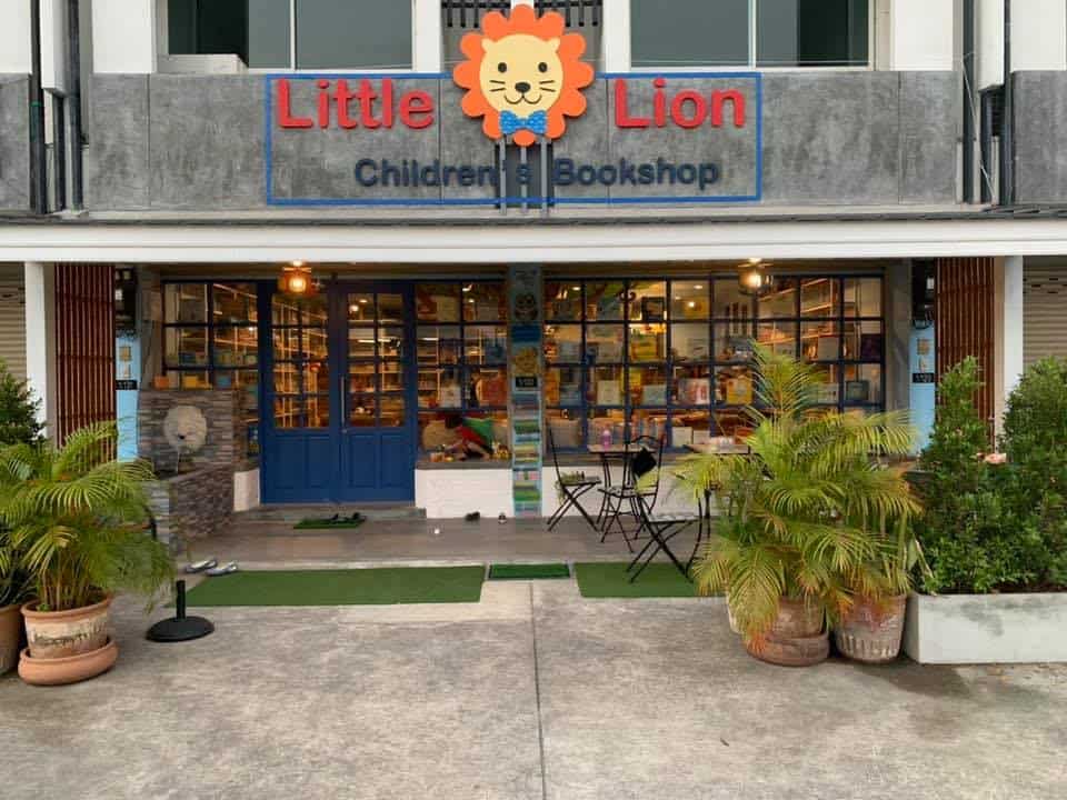 Storefront of Little Lion's Children's Bookshop with its lion sign, blue doors and potted palms in Hang Dong