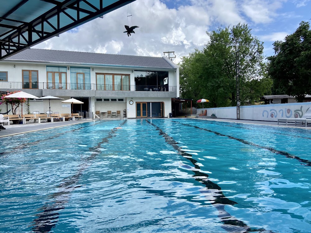 Looper's outdoor lap pool at water level, with lane markings and poolside loungers beside a white two-story building