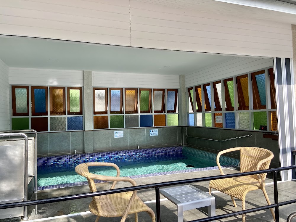 Bubbling indoor jacuzzi pool with colorful patterned-glass windows and rattan chairs at Looper