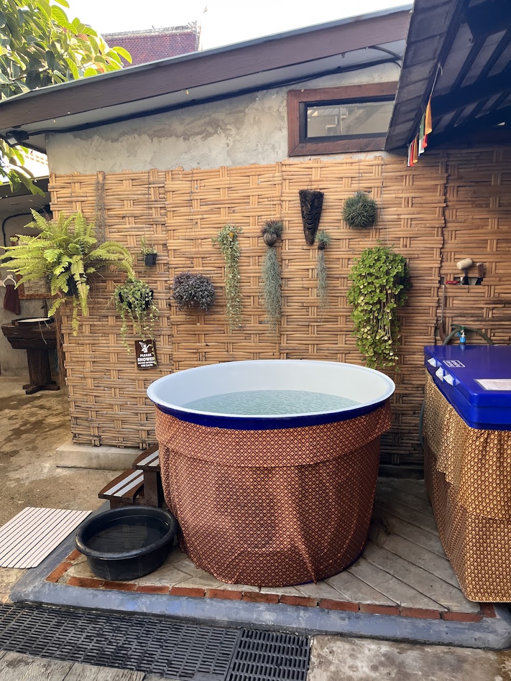 Outdoor round copper soaking tub at The Old City Spa against a bamboo wall hung with ferns