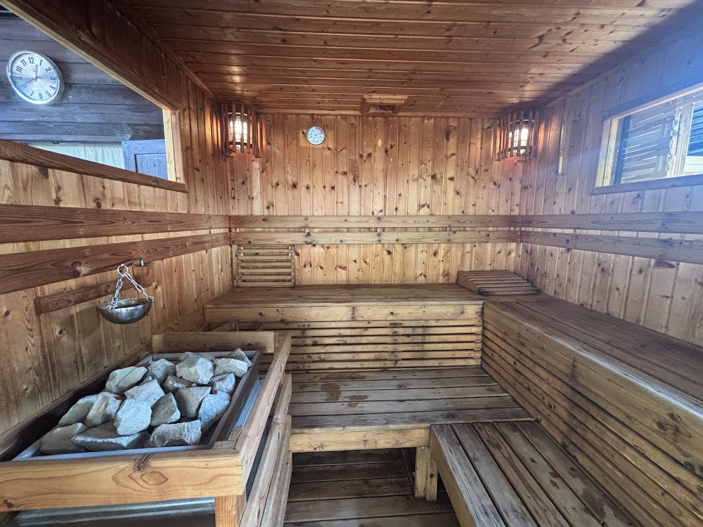 Pine-clad sauna room at The Old City Spa with tiered benches and a rock-filled heater box