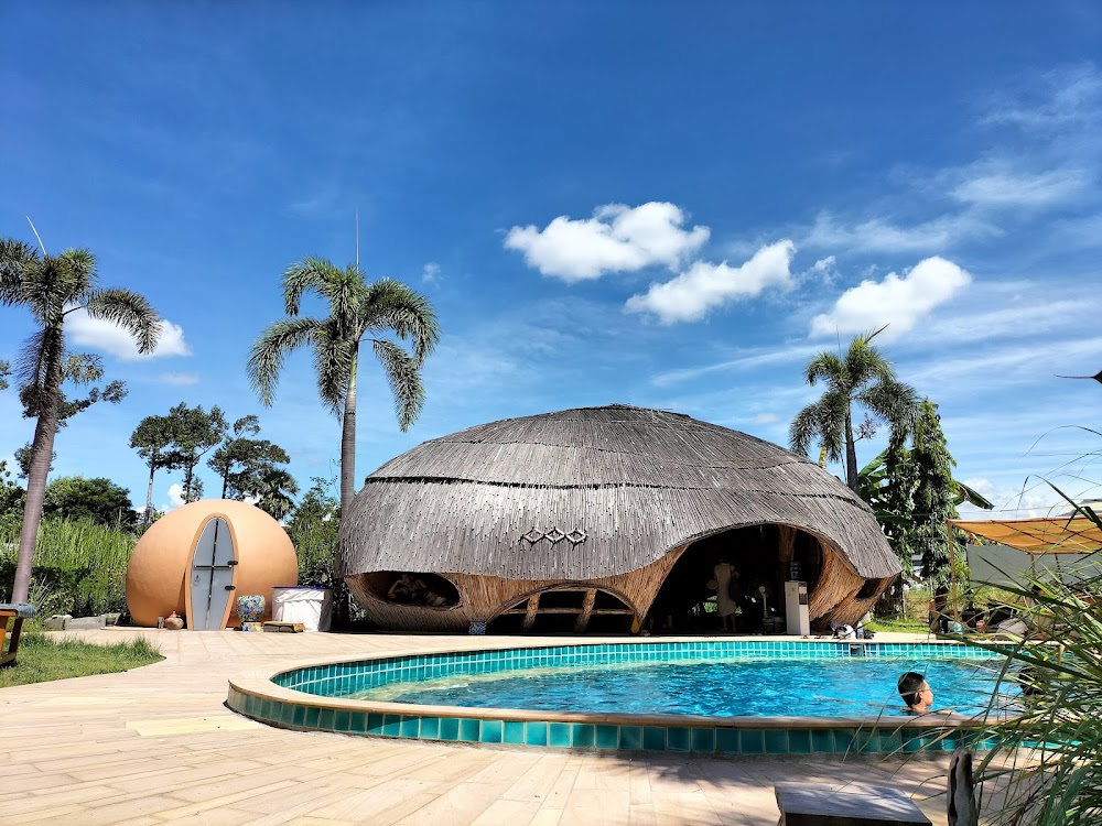 Thatched dome bamboo sauna beside a turquoise pool and earthen dome hut at The Cocoon