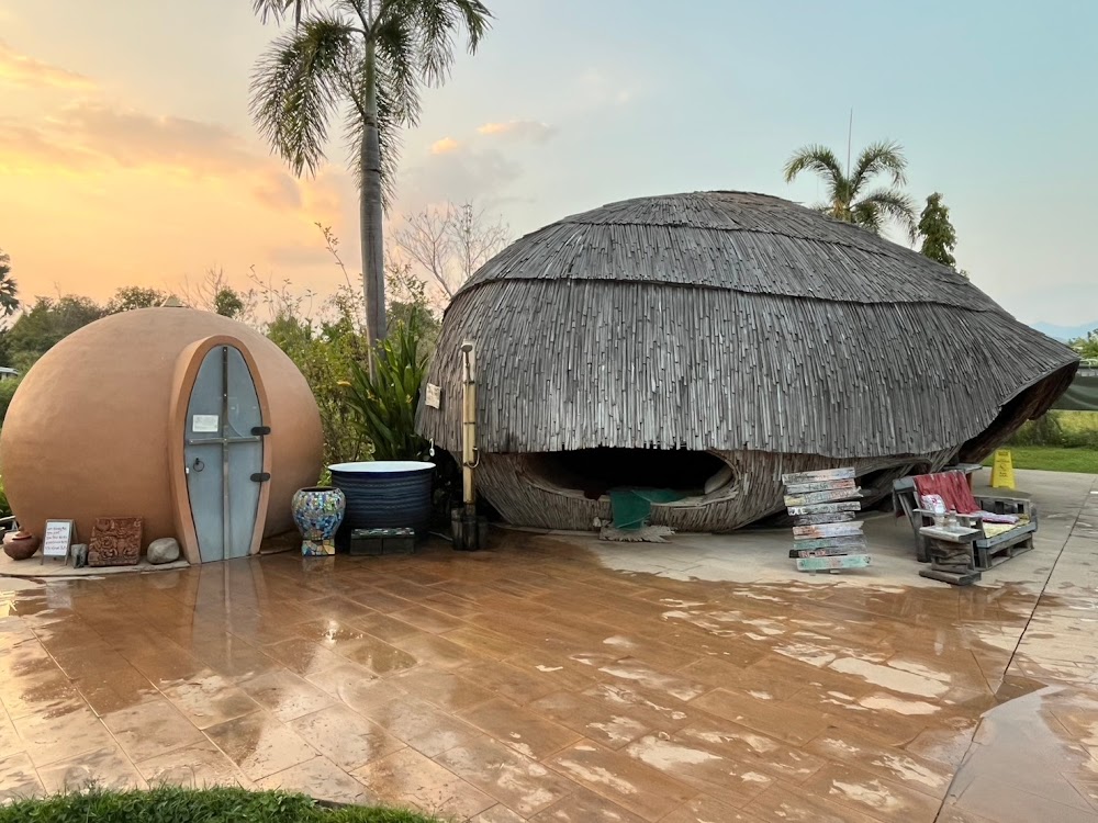 Earthen dome hut and bamboo dome sauna on a tiled patio at sunset at The Cocoon
