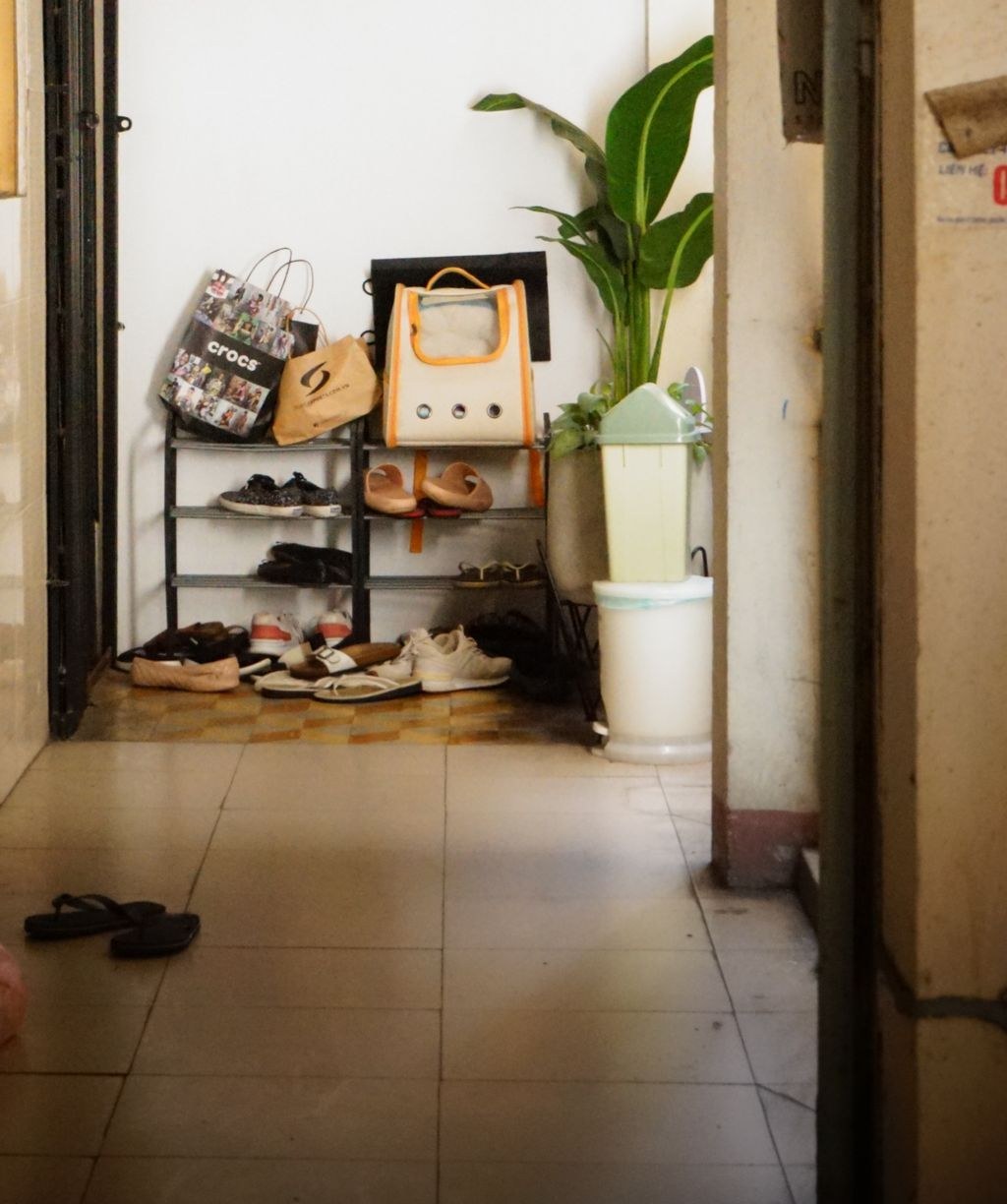 An overflowing shoe rack and shoes scattered by a Chiang Mai apartment doorway