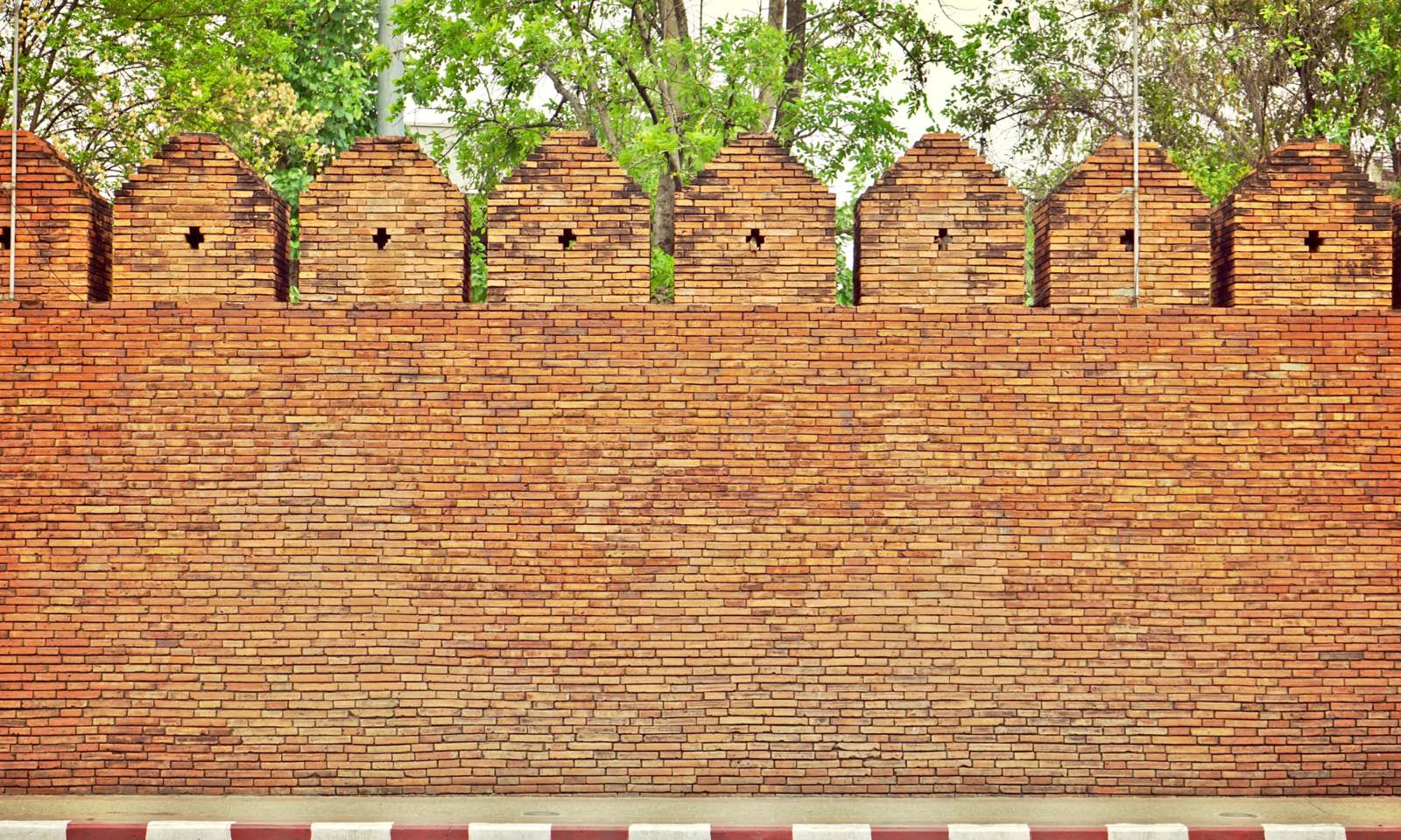 Chiang Mai's old-city brick wall with crenellated battlements and roadside trees
