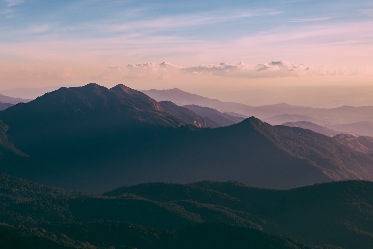 Layered forested mountain ridges under a soft dusk sky near Chiang Mai