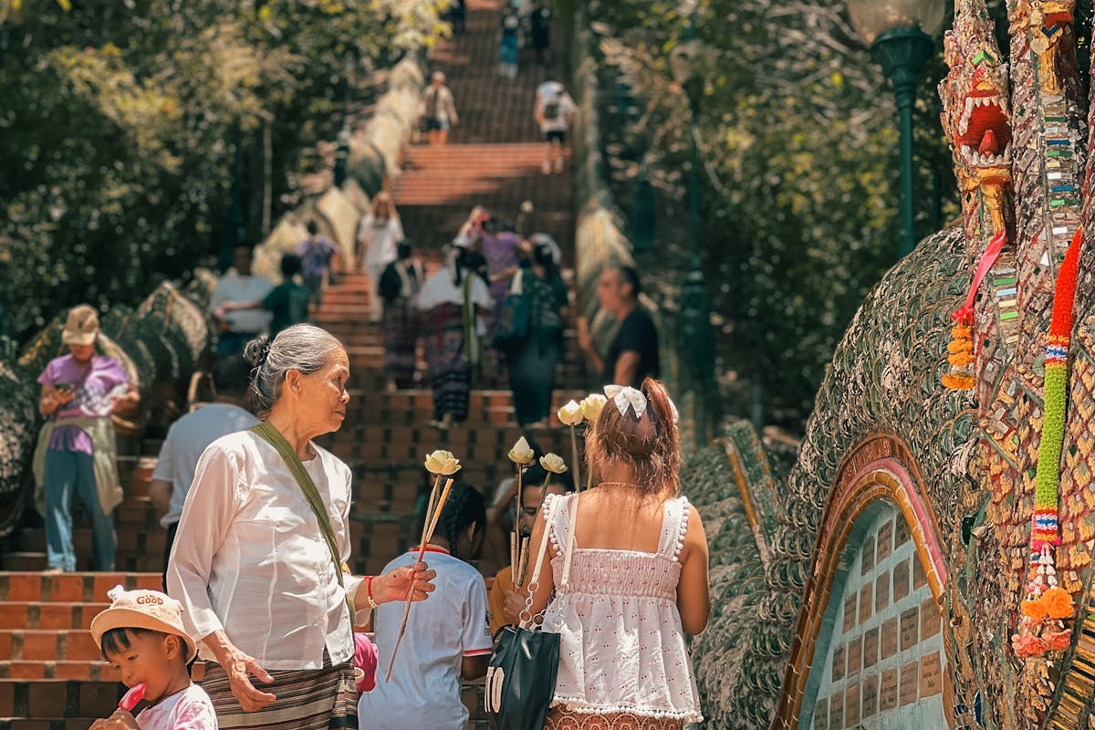 Visitors climbing the naga staircase at Doi Suthep temple, one holding lotus flowers
