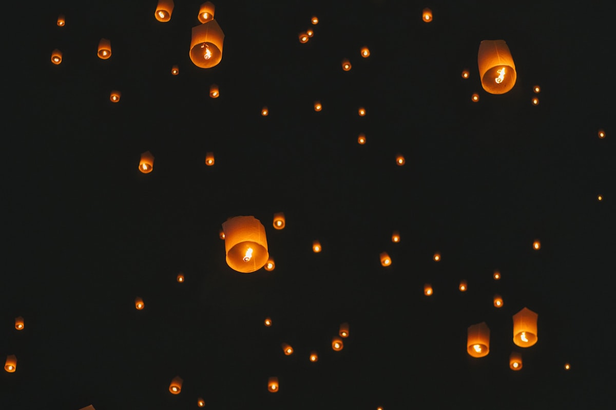 Glowing Yi Peng sky lanterns floating against a black night sky